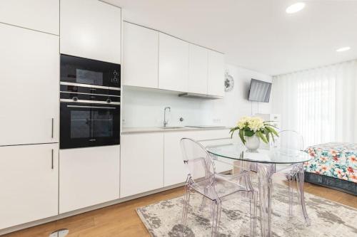 a white kitchen with a glass table and chairs at Studio Sweet Dreams in Aveiro touristic center in Aveiro