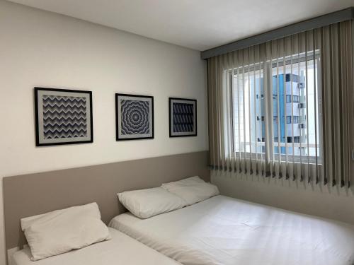 two beds in a room with a window and a window at Apto Promenade I PONTA VERDE in Maceió