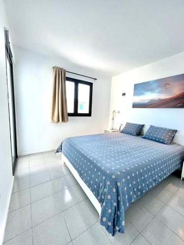 a bedroom with a bed with a blue comforter at Casa Atika in Los Pocillos