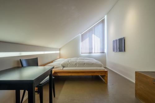 Schlafzimmer mit einem Bett, einem Tisch und einem Fenster in der Unterkunft Wirtshaus Rütihof in Gränichen
