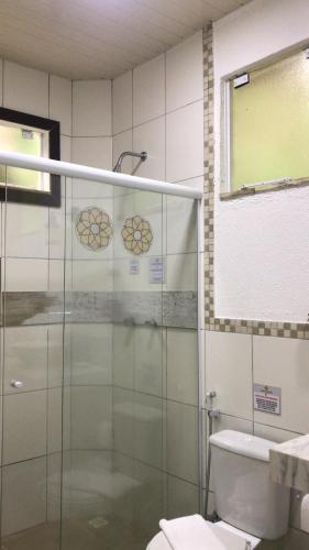 a bathroom with a glass shower and a toilet at Pousada Reserva Penedo in Penedo