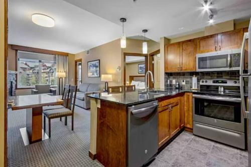 a kitchen with wooden cabinets and a table and a dining room at Falcon Crest Lodge 1 BR Condo With Gym & Hot-Tubs & Mountain View in Canmore