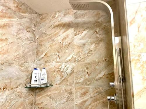 een badkamer met 2 shampooflessen op een stenen muur bij Mountain View 1 BR Condo With Gym & Hot-Tubs in Canmore