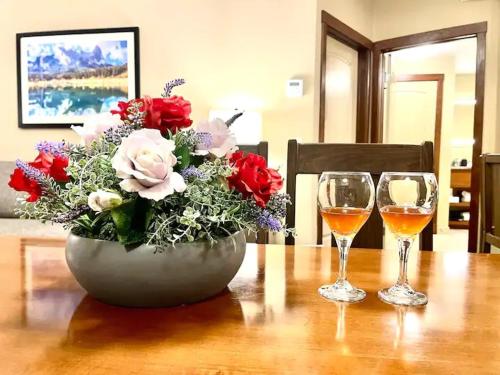 a vase of flowers and two wine glasses on a table at Falcon Crest Lodge 1 BR Condo With Gym & Hot-Tubs & Mountain View in Canmore