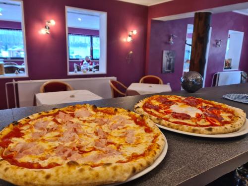 two pizzas sitting on a table in a restaurant at Pizzeria Pension Damiano in Muldenhammer