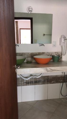 a bathroom with two bowls on a counter with a mirror at Pousada Reserva Penedo in Penedo