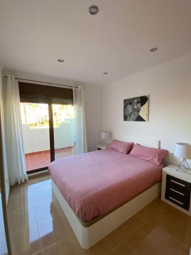 - une chambre avec un lit avec des draps roses et une fenêtre dans l'établissement Apartamento Vera Playa, à Vera