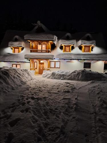 een huis bedekt met sneeuw 's nachts bij Dworek na skraju lasu in Kościelisko