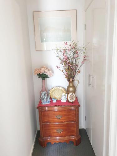 a wooden dresser with vases and flowers on it at Room in Officer in Officer