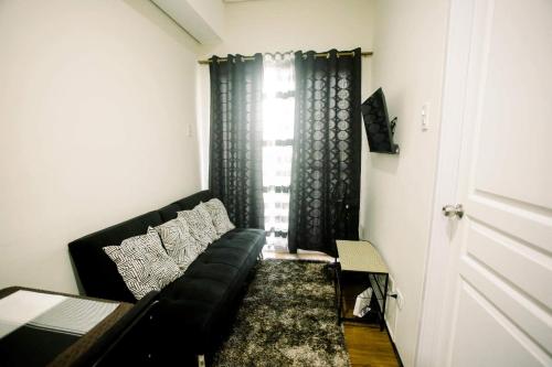 uma sala de estar com um sofá preto e uma janela em JHS condotel em Roxas