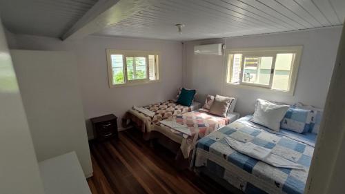 a bedroom with two beds and two windows at Casa espaçosa em Bento Gonçalves in Bento Gonçalves