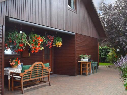a patio with a bench and flowers hanging from a building at Kranich-Holzferienhaus 'Kleine Auszeit' in Rehden