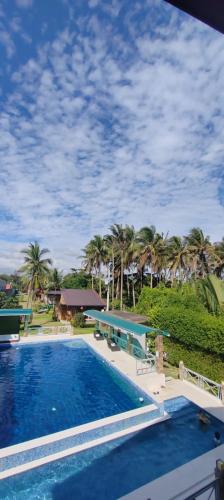 a large swimming pool with palm trees in the background at Nahas Beach Resort in Abung