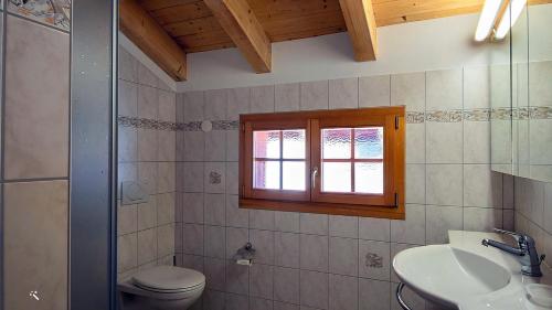 łazienka z toaletą, umywalką i oknem w obiekcie Cresta w mieście Fiesch