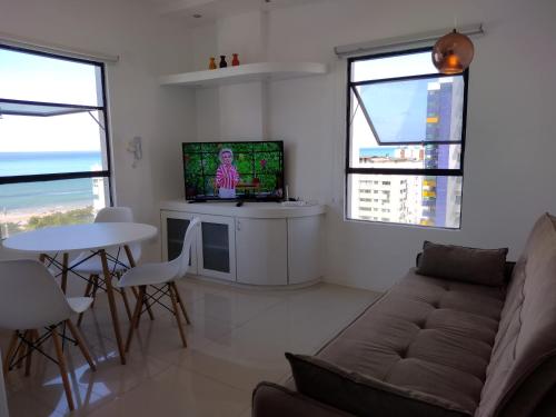 uma sala de estar com um sofá, uma televisão e uma mesa em Apto de frente para o Mar, Piscina na cobertura em Recife