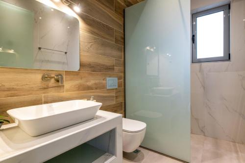 a bathroom with a sink and a toilet and a shower at Villa Elite Kalathos by Villa Plus in Kalathos