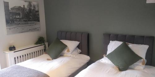 um quarto com 2 camas com lençóis brancos e almofadas verdes em Free Derry Apartments em Derry