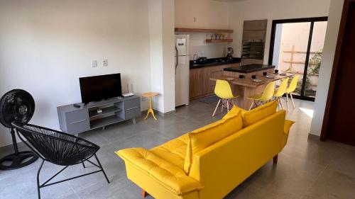 a living room with a yellow couch and a kitchen at Casa em Garopaba in Garopaba