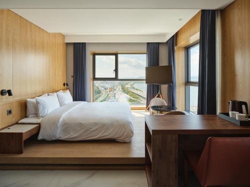 Hotel tt Gupo في بوسان: غرفة نوم بسرير ومكتب ونافذة