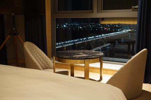 a room with a bed and a table and a window at Hotel tt Gupo in Busan