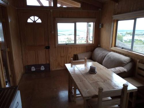 a living room with a wooden table and a couch at Cabañas La Frontera. in Puerto Natales