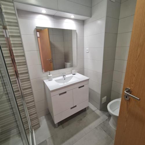 a bathroom with a sink and a mirror and a toilet at MARIACAST CLUBE DA PRAIA DA ROCHA in Portimão