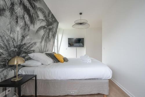 - une chambre avec un lit blanc et du papier peint en palmier dans l'établissement *Disneyland-Paris* duplex 7pers, Parking, Wifi, Netflix, à Serris