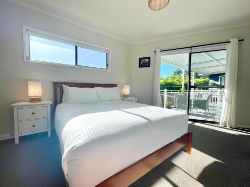 een slaapkamer met een groot wit bed en een raam bij Blue Lily Bungalow in Katoomba