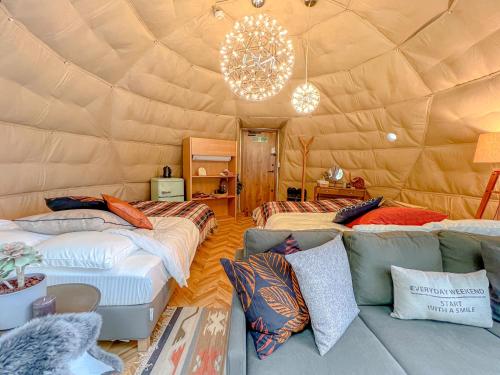 a room with three beds and a couch in a yurt at ファームグランピング　ル・クロ　かいづか　いぶきヴィレッジ in Kaizuka