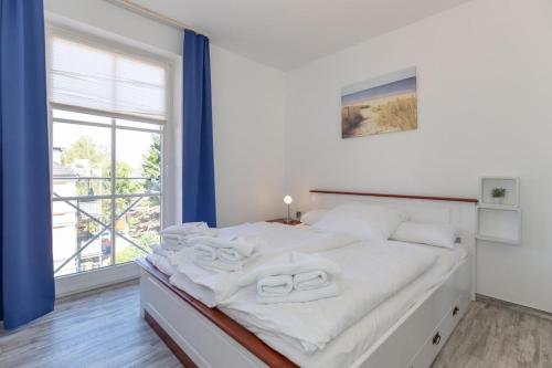 a white bedroom with a bed with two towels on it at Strandstrasse-43-Wohnung-25-157 in Kühlungsborn