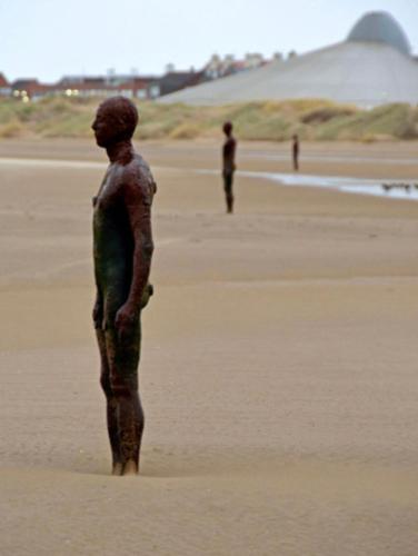 a statue of a person standing on a beach at Crosby Apartments in Liverpool