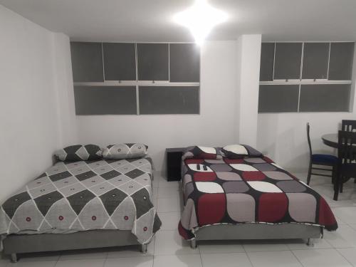 a bedroom with two beds and a table and chairs at Ambigua Hospedaje in Trujillo