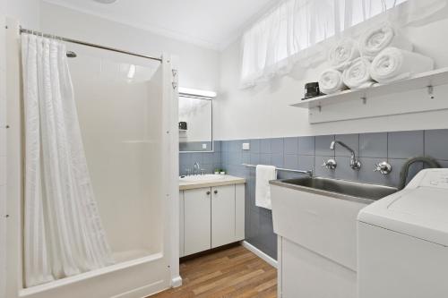a white bathroom with a sink and a shower at Ocean Bridge Lakes Entrance in Lakes Entrance