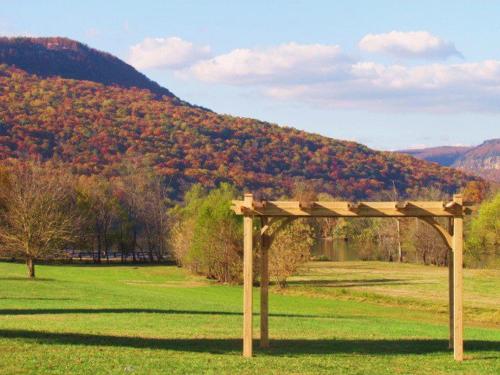 a wooden pergola in a field with a mountain at Signal Mountain Room at Tennessee RiverPlace in Chattanooga