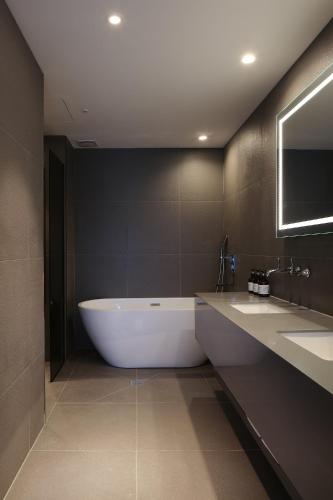 a large bathroom with a tub and two sinks at Hotel tt Gupo in Busan