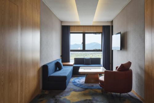 a living room with a blue couch and a table and chairs at Hotel tt Gupo in Busan