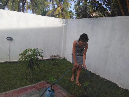 a woman watering a garden with a hose at VILLA ARIANNA in Wattala