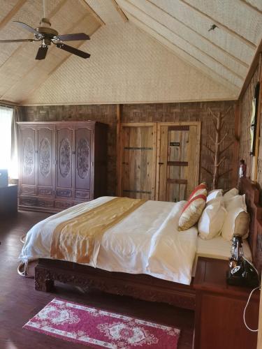 a bedroom with a bed and a ceiling fan at Dai Yuan Inn in Mengla