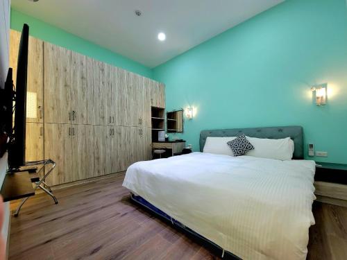 Un dormitorio con una gran cama blanca y una pared azul en 翠綠色民宿, en Feng-li