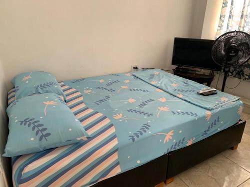 a bed with a blue comforter with flowers on it at Hotel Alférez Real - Jamundí in Jamundí