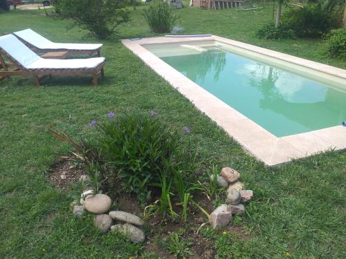 una piscina en un patio con un banco al lado en Arrullo del viento en Villa Yacanto