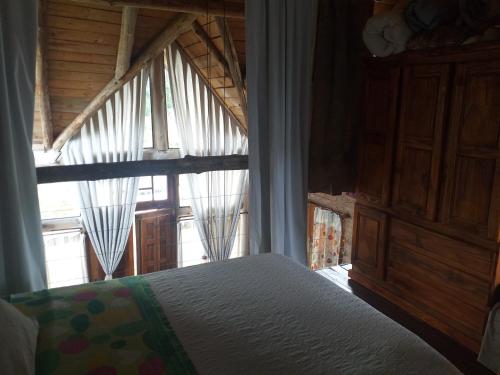 1 dormitorio con cama y ventana grande en Arrullo del viento en Villa Yacanto