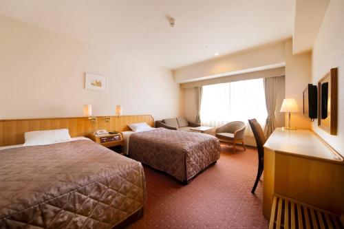 a hotel room with two beds and a living room at Hotel Crown Palais Hamamatsu in Hamamatsu
