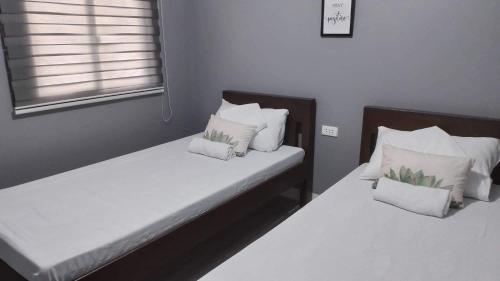2 Betten in einem Zimmer mit weißer Bettwäsche und Kissen in der Unterkunft The Tent Sipalay in Sipalay