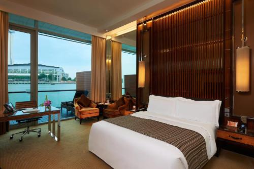 a bedroom with a large bed and a large window at The Fullerton Hotel Singapore in Singapore
