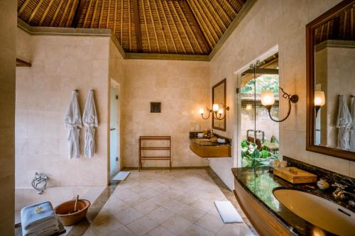 ein Badezimmer mit Badewanne, Waschbecken und Spiegel in der Unterkunft Puri Wulandari A Boutique Resort & Spa in Ubud