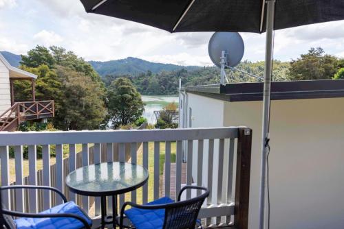 a balcony with a table and chairs and an umbrella at Rowling Road Studio in Kaiteriteri