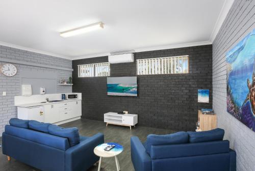 a living room with two blue couches and a kitchen at Pyramid Holiday Park in Tweed Heads
