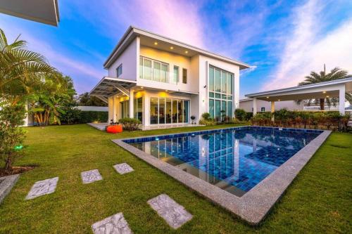 a house with a swimming pool in front of it at Modern 3 bedroom Pool Villa PG19 in Cha Am