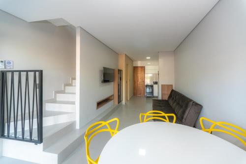 a living room with yellow chairs and a staircase at Pousada Soul Papagaio - lofts completos a 30 metros do mar in Palhoça